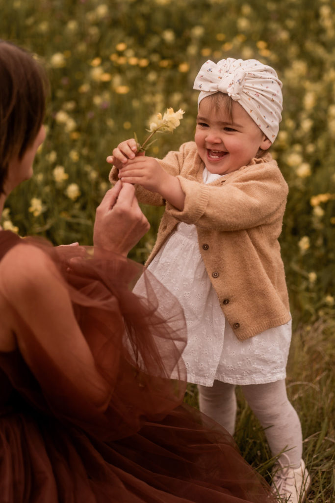 Kleines Mädchen überreicht Mama eine Blume bei einem Mummy-and-me-Shooting von PIC@MO mit Mona von Malm