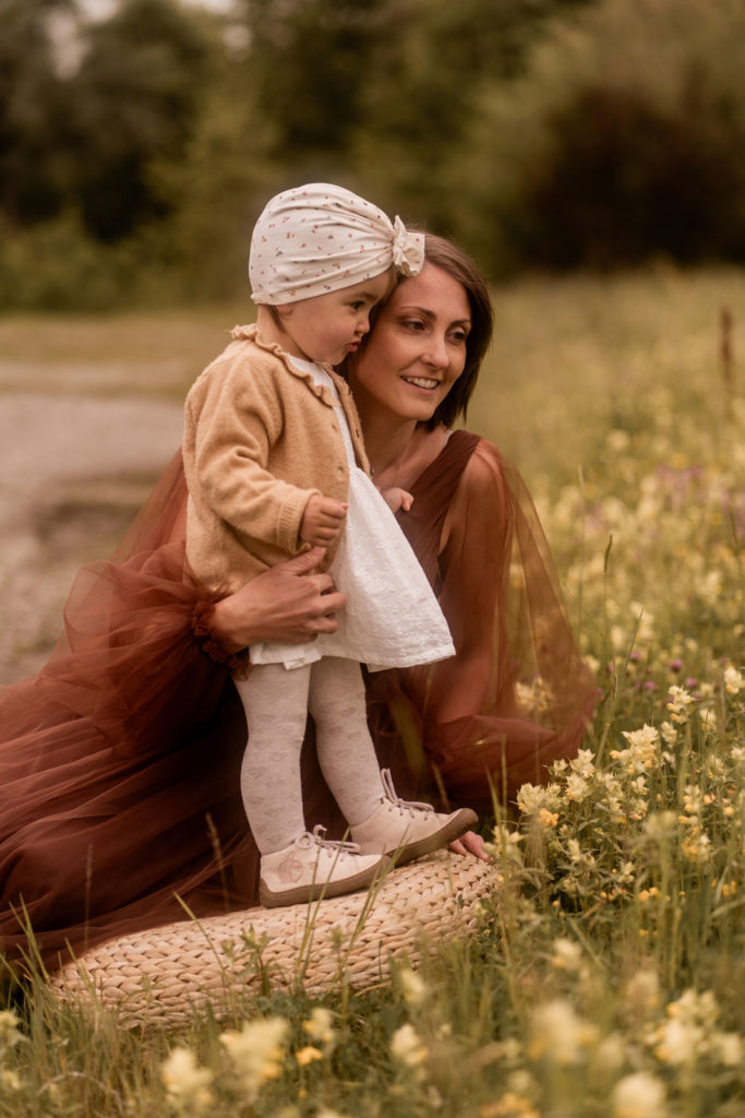 Mutter und kleines Mädchen sitzen auf einer Wiese und schauen in die Ferne bei einem Mummy-and-me-Shooting von PIC@MO mit Mona von Malm